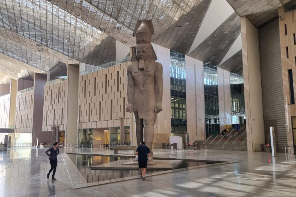 Landscape photograph depicting the a colossal 30 foot high granite statue of King Ramses II exhibited in the entrance hall of the Grand Egyptian Museum