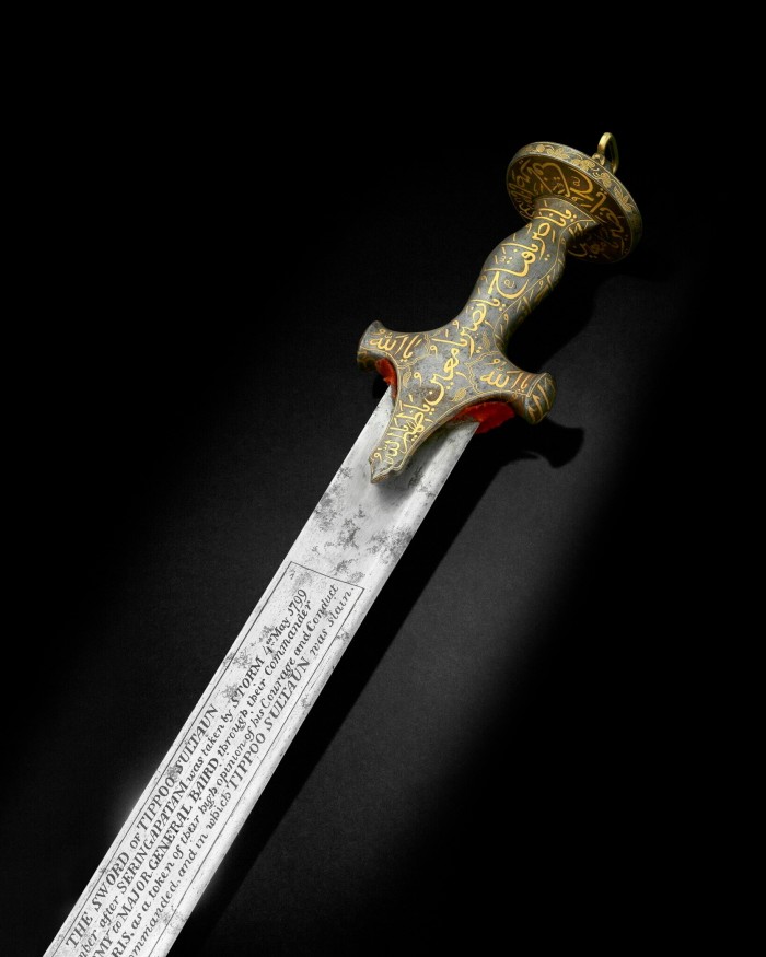 A sword is engraved with patterns and words on its blade and handle