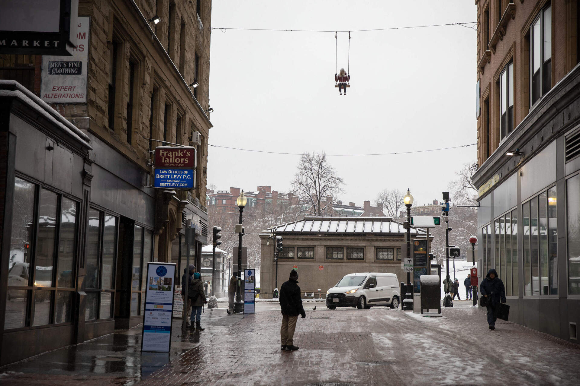 Pedestrians on Winter Street look up at a Mark Jenkins untitled sculpture of a woman on a swing. (Robin Lubbock/WBUR)