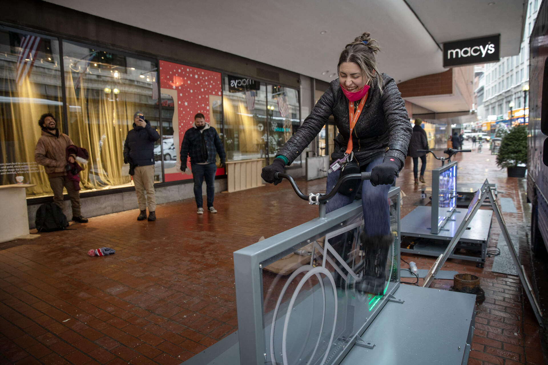 Cheri Cresta, from Revere, takes a moment to ride a Light Lane Custom Bike on the Summer Street Pedestrian Plaza. She laughs as, when she pedals, the bicycle blasts out a Boston tune. (Robin Lubbock/WBUR)