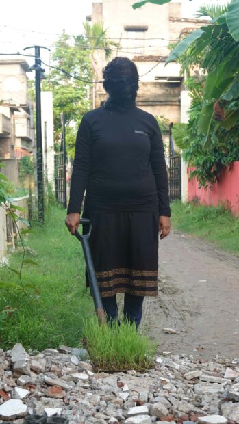 Photo of a woman in a veil standing with a shovel
