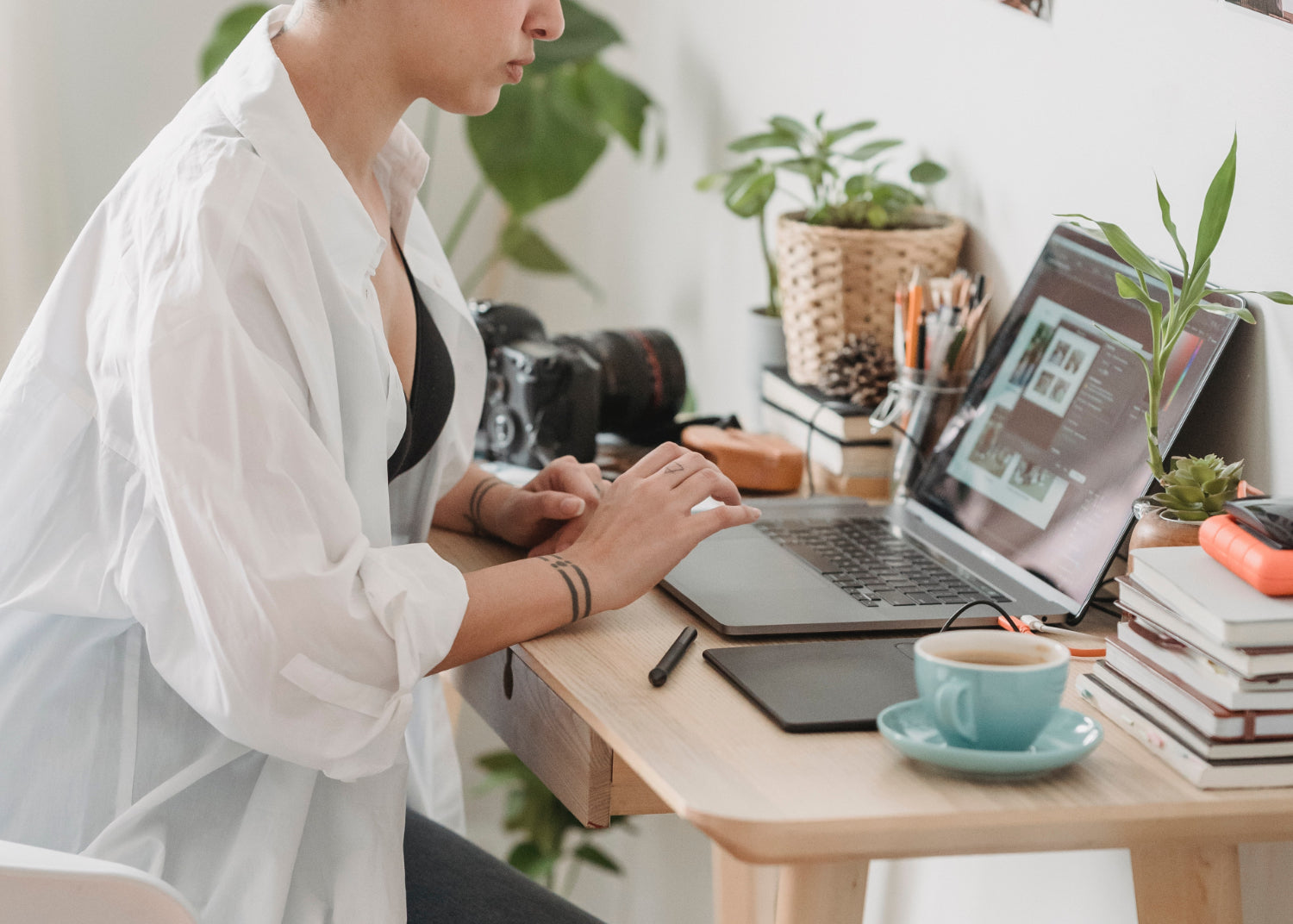 A woman sits at a desk typing on a laptop