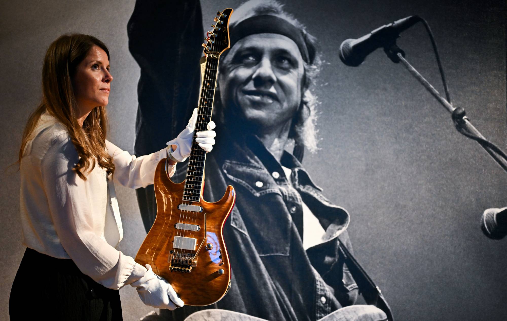 Christie's Head of Sales, Specialist Head of the Private & Iconic Collections department Amelia Walker shows a Pensa-Suhr New York 1988 guitar during the pre-sale exhibition of guitars from the personal collection of British singer and guitarist Mark Knopfler at Christie's auction house in London, on January 26, 2024. (Photo by Ben Stansall / AFP) (Photo by BEN STANSALL/AFP via Getty Images)