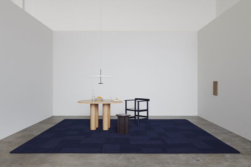 tone on tone navy blue rug with round table, dining chair, side table, and pendant lighting
