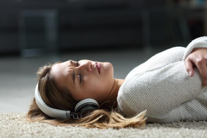 Sad woman with headphones on lying on the floor