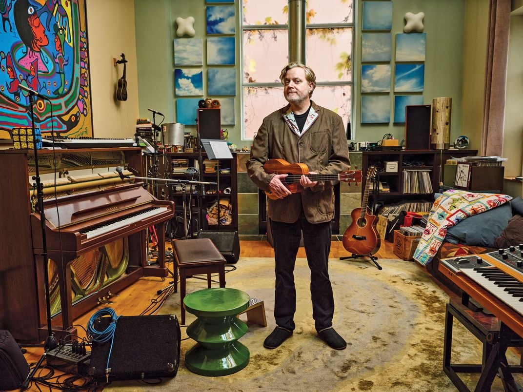 Kevin Hearn, rock instrumentalist and self-trained art fraud investigator, at his home in Toronto with an authentic Morrisseau: Shaman’s Dream, 1995.