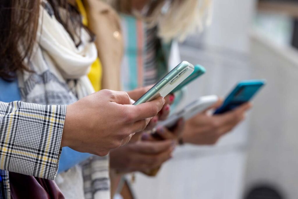 Close up of a group of women using their smartphones, representing the social media class actions and settlements.