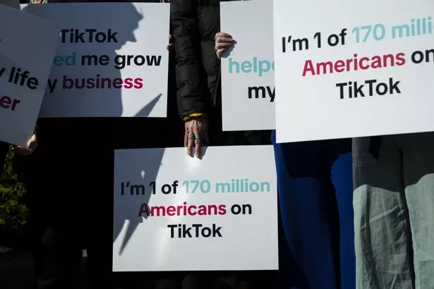 A group of TikTok creators and advocates hold signs before a news conference outside the US Capitol on Tuesday