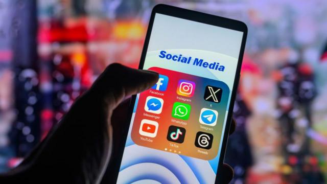 The Facebook app logo is being displayed on a smartphone among other social media networks
