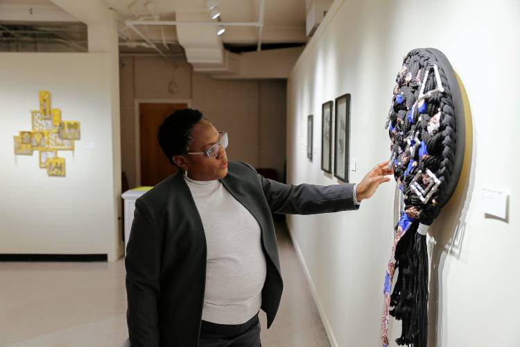 Curator and UMass art professor Juana Valdes, seen here with work by Chire “Vanta Black” Regans at “As We Move Forward,” says the UMass exhibit is designed to honor the legacy of Augusta Savage, the seminal Black sculptor who was born in Florida.