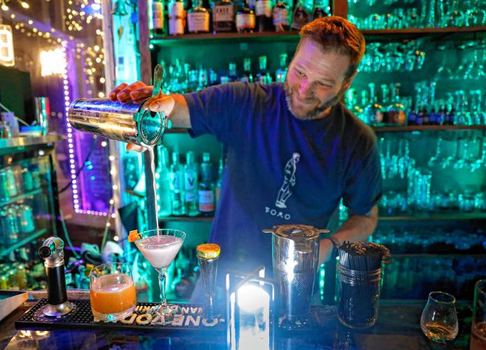 Owner Ed Mooers pours a round of cocktails at Valley Art Supplies on Friday night in Easthampton. The business opened a bar using some of their Cottage Street space last July. 