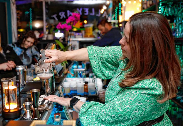 Owner Juliette Mooers pours a cocktail Friday night behind the bar at Valley Art Supplies in Easthampton.