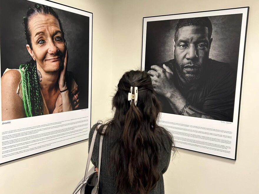View of a woman with dark hair pulled back in a clip looking at an image of a woman and an image of a man. 