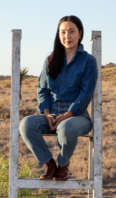 Daisy Nam sits on a ladder in field.