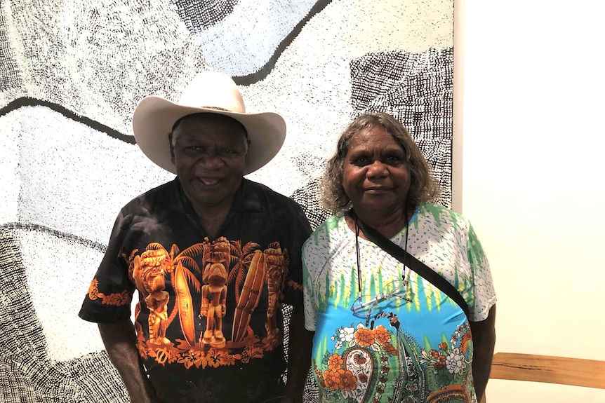 a smiling couple in front of art
