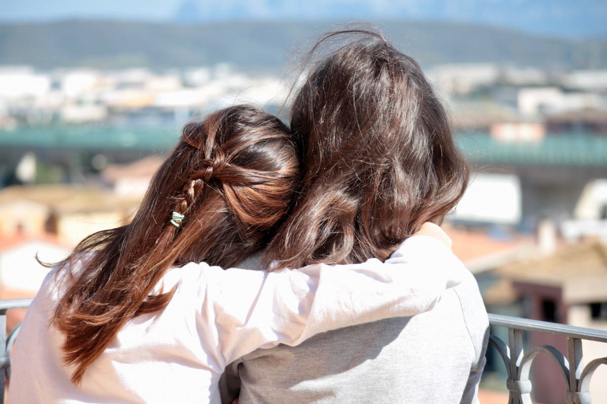 A photo of one person putting their arm around another person, designed to represent attachment theory.
