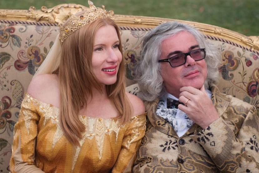 Two people is flamboyant costumes sitting on a couch.