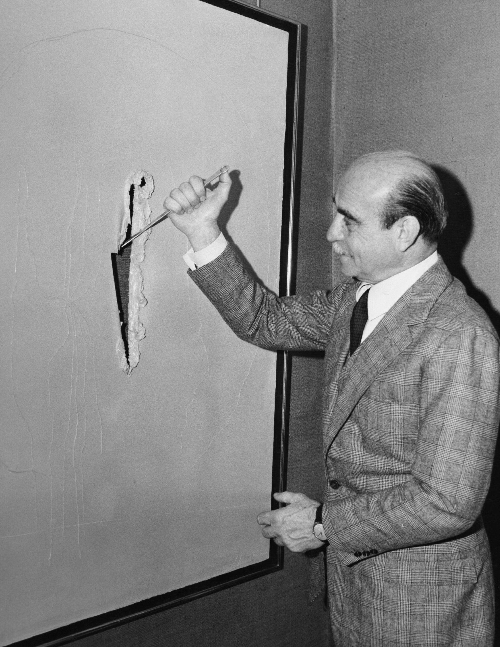 Black and white photo of man slashing painting canvas