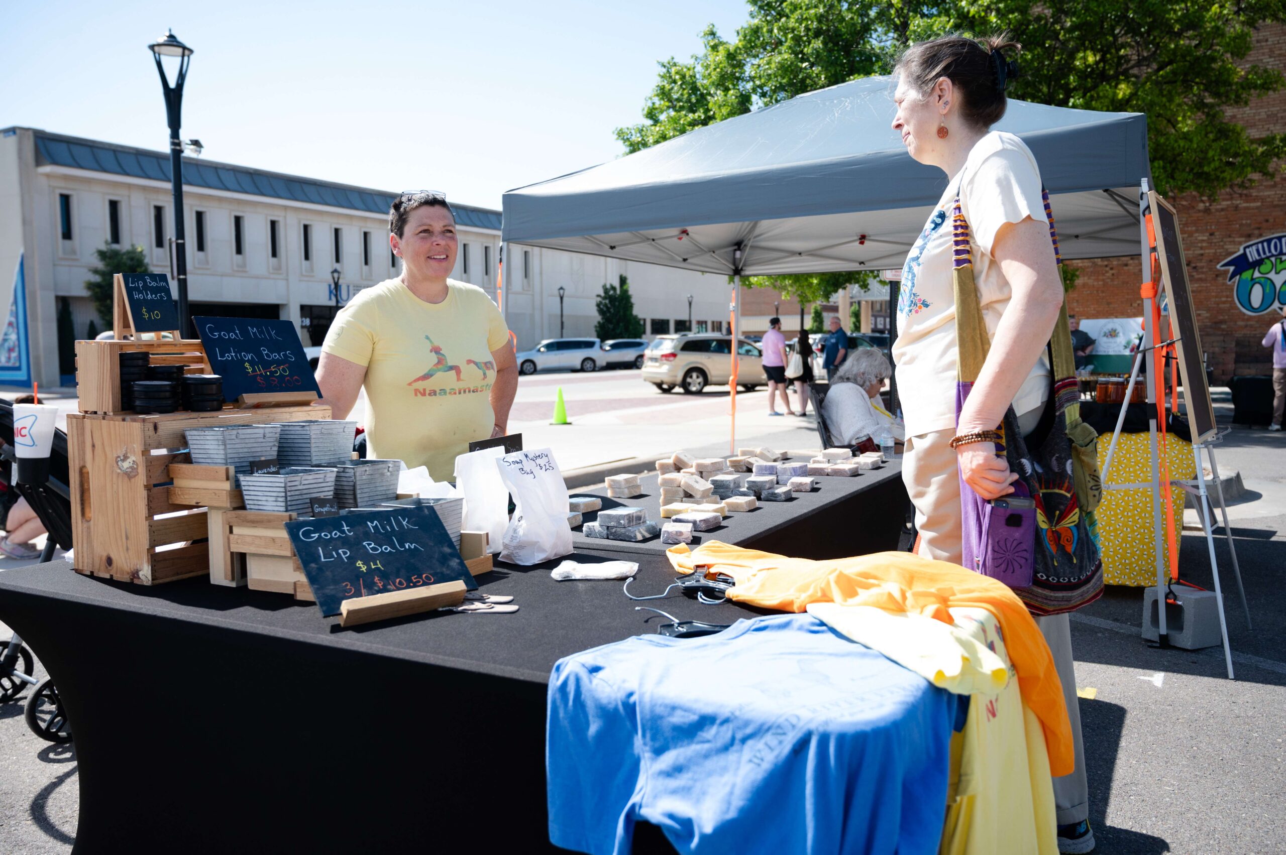 Wind River Farm owner Angela Price (left) chats with a customer, Willow Leenders (right) about the benefits of using goat-milk soap during the first Farm and Art Market Downtown on Saturday, May 18, near City Lights Stage in Salina. <b>Photo by Olivia Bergmeier</b>