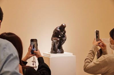 People take photographs of a small version of Rodin's Thinker. 