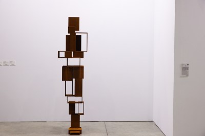 A corten steel abstract sculpture stands in an art fair booth. 