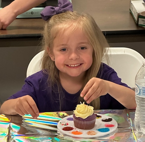 Little girl decorating a cupcake