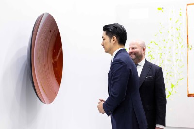 Two men in suits look at a concave sculputre. 