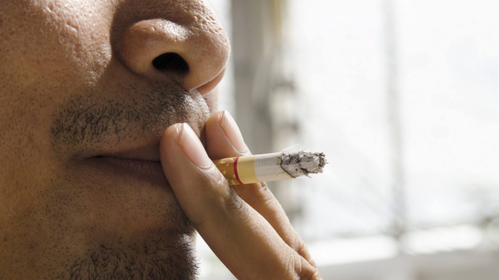 closeup of a man smoking a cigarette in his mouth