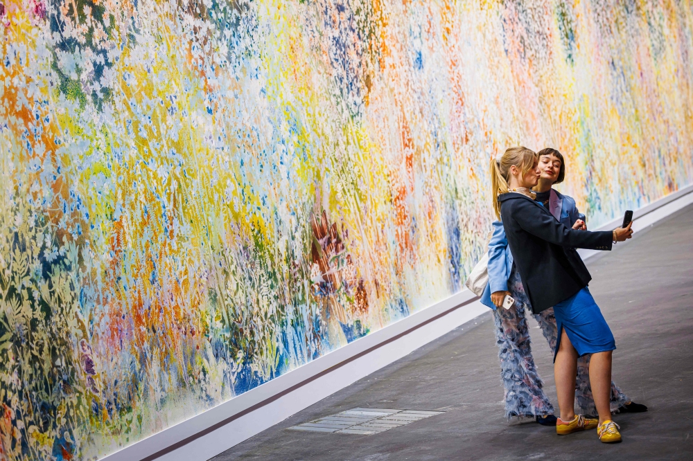 Visitors take a selfie in front of ‘Spring to Fall’ 2023/2024, by American artist Sam Falls displayed at the Unlimited sector of Art Basel fair for Modern and contemporary art, in Basel June 11, 2024. — Valentin Flauraud/AFP pic