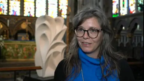BBC Jess Richards standing in a church in front of a white sculpture
