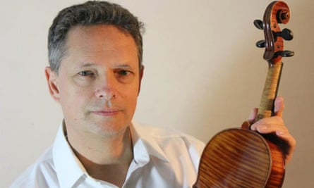 Matthew Gryspeerdt holds up a violin as he poses for a photo