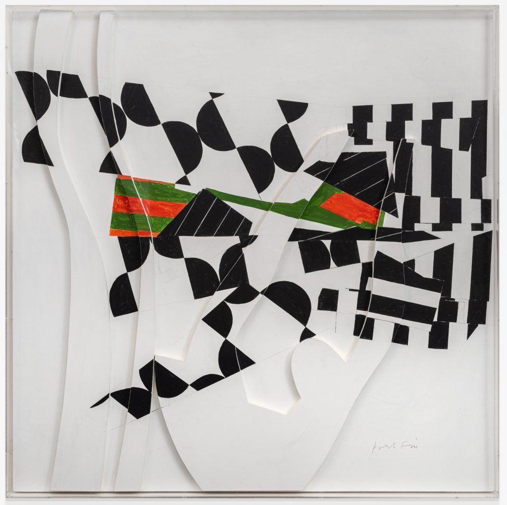 a white stretch of wood with raised bits also white and a pattern drawn over the to in black with patches of green and red