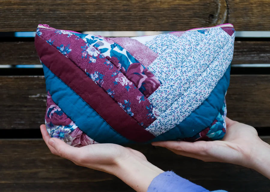 Close up of a person's hands holding a quilted cosmetic case