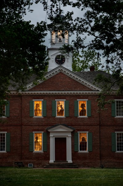 View of a courthouse with silhouettes in five of the windows. 