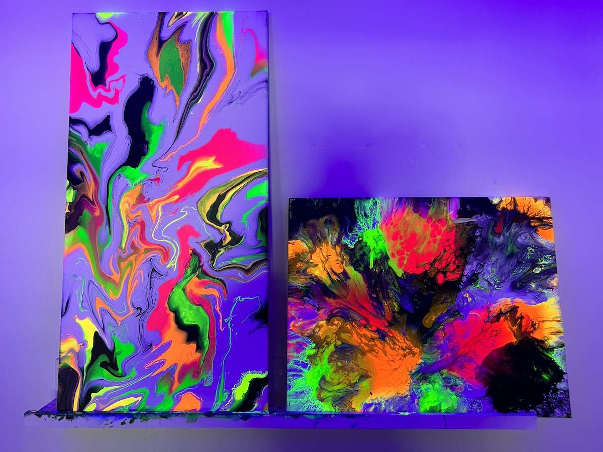 two painted canvases under black light