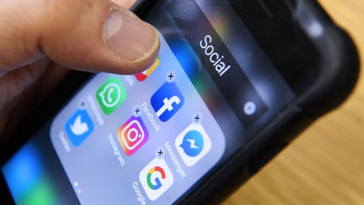 <div>A man holds a smartphone with the icons for the social networking apps. (KIRILL KUDRYAVTSEV/AFP via Getty Images)</div>
