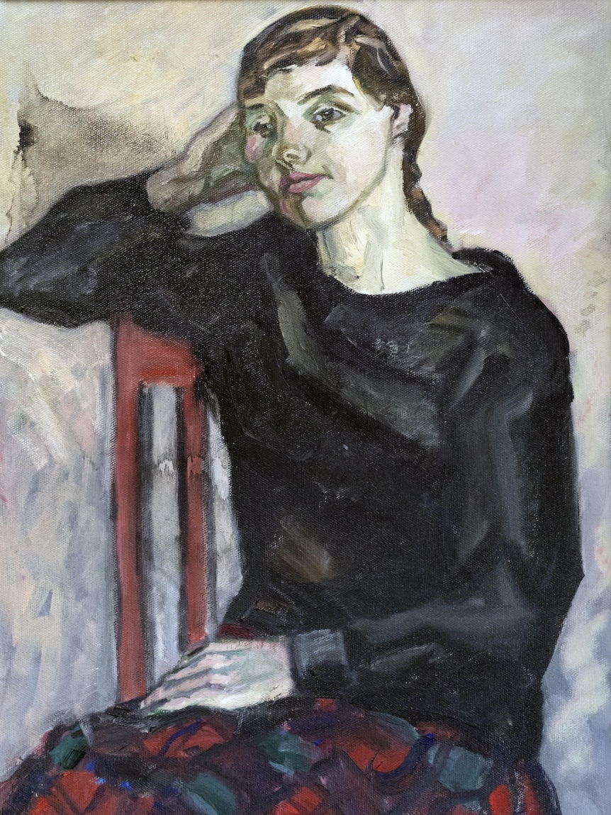 A painting in muted colours of a woman resting her head on her hand while sitting in a red chair.