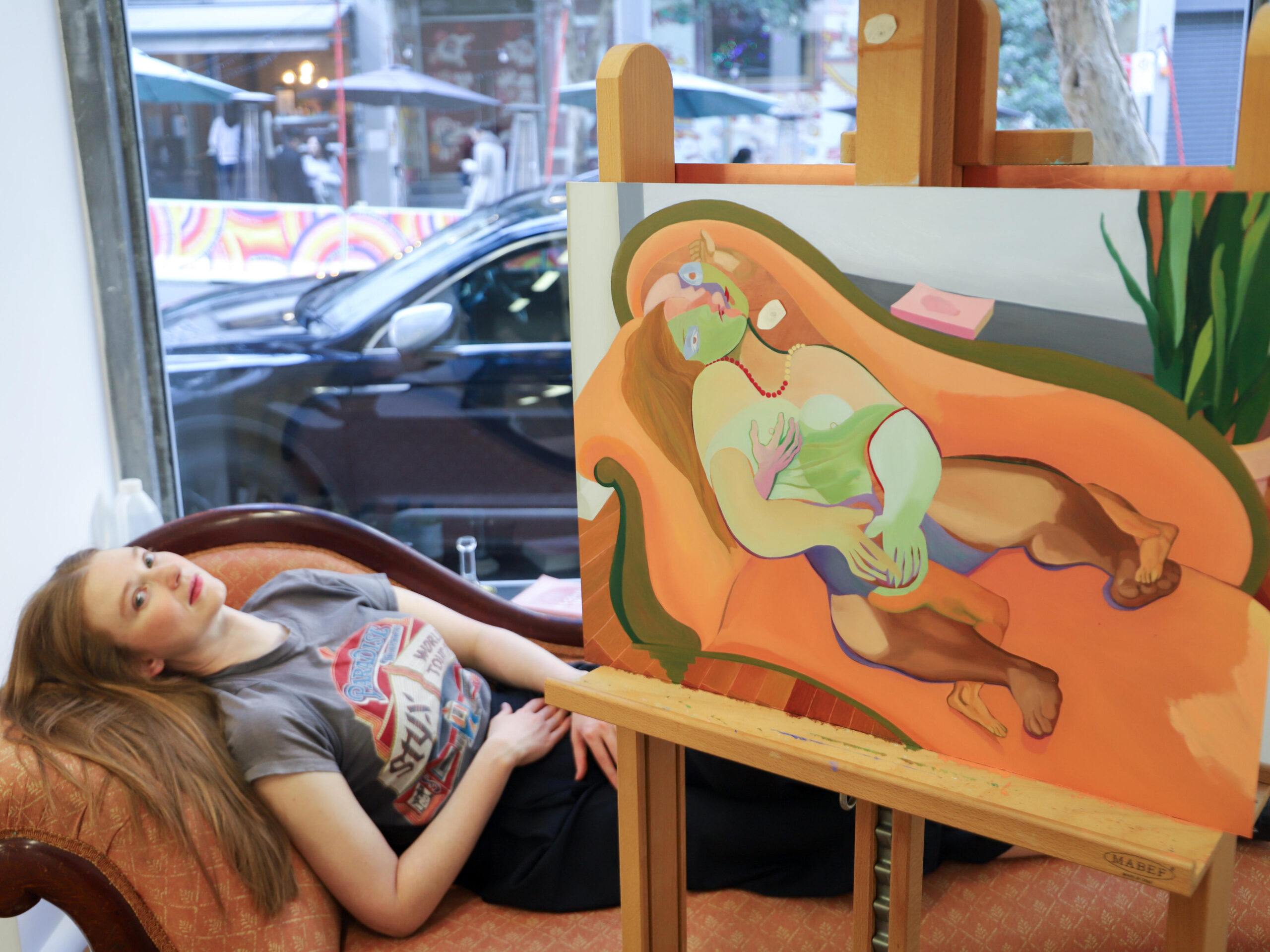 Author Bri Lee lies on a couch in the background, with foreground showing the Picasso-style portrait of her 