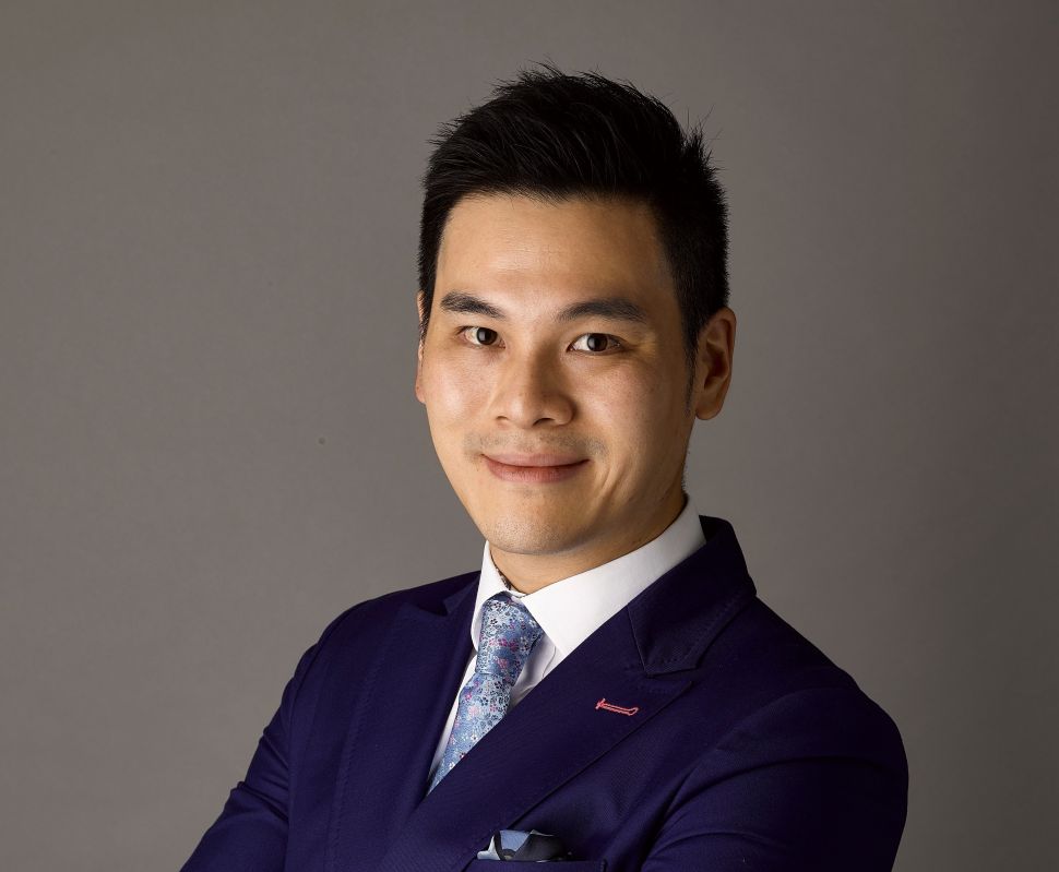 Portrait of an Asian young man wearing a blue suit. Kwok is a leading auctioneer and holds a key role in Sotheby's expansion in tehe Asian Region 