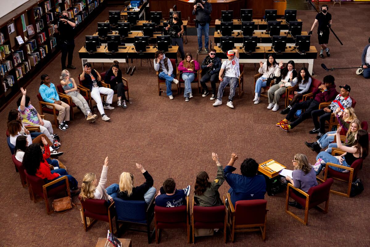 Students sitting in chairs arranged in a circle in a library.