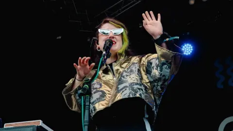 Kirsty McClachlan Heledd Watkins, wearing sunglasses and a gold jacket, performs at Green Man