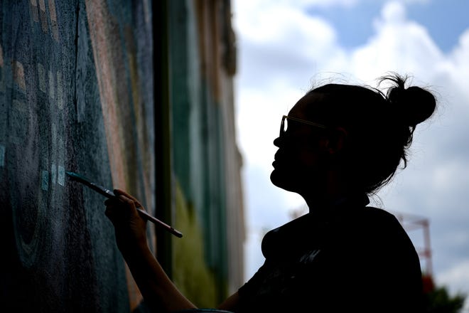 Megan Lingerfelt, one of four local artists chosen to participate in KnoxWalls at Emory Place, works on her piece at the outdoor art destination in Knoxville, Thursday, August 15, 2024. The immersive joint art collaboration from artists based nationwide will open to the public in Knoxville on Friday, Oct. 4.