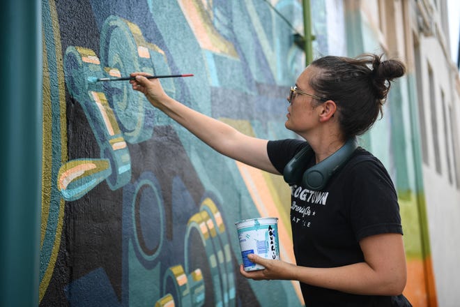 Megan Lingerfelt, one of four local artists chosen to participate in KnoxWalls at Emory Place, works on her piece at the outdoor art destination in Knoxville, Thursday, August 15, 2024. The immersive joint art collaboration from artists based nationwide will open to the public in Knoxville on Friday, Oct. 4.