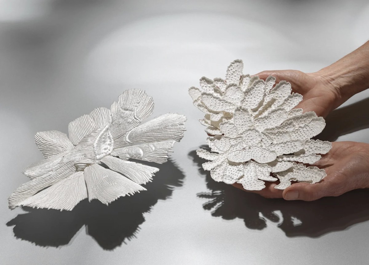 Hands holding two pieces of sterling silver sculpture in natural forms.