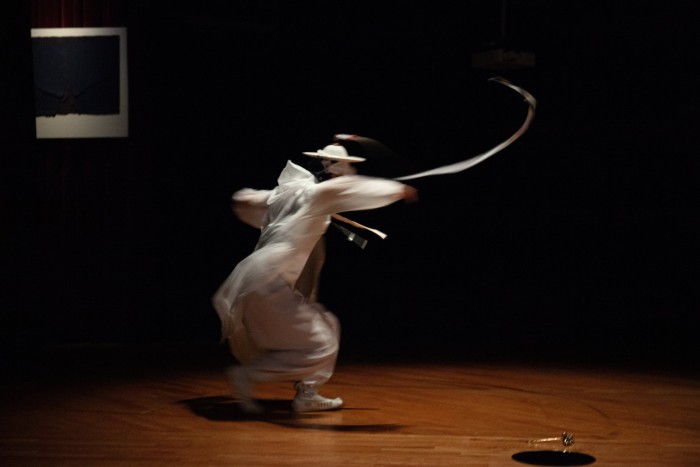 A person in baggy white trousers and a white top whirls around