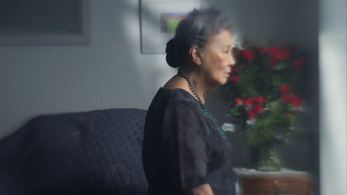 An older woman wearing a black blouse looking sad and somewhat blurry