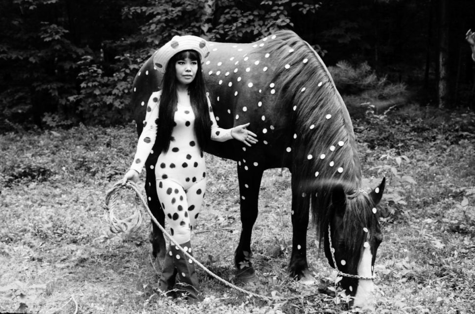 Yayoi kusama japanese woman walking with a horse covered with polka dots.