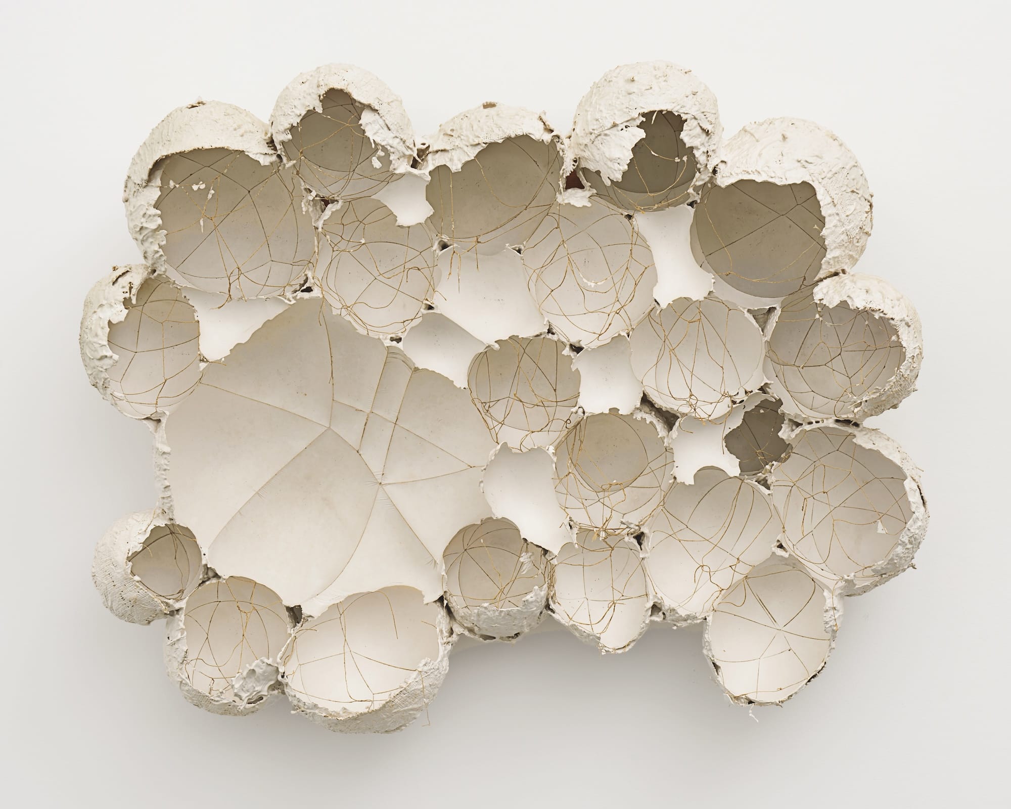 an abstract wall sculpture made of plaster that has been formed around balloons or other objects