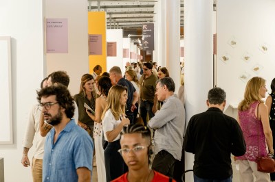 People walking through the aisles of an art fair. 