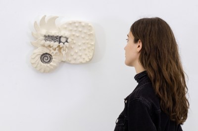 A woman looks at a white sculpture. 